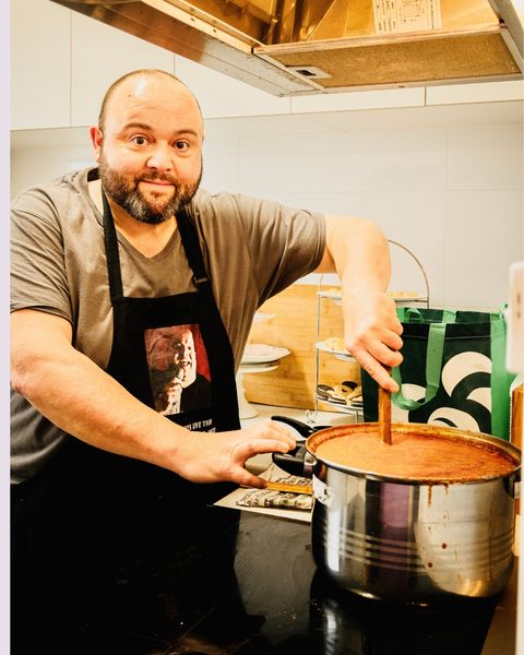 Cooking in the kitchen — stirring a big pot of sauce on the stove